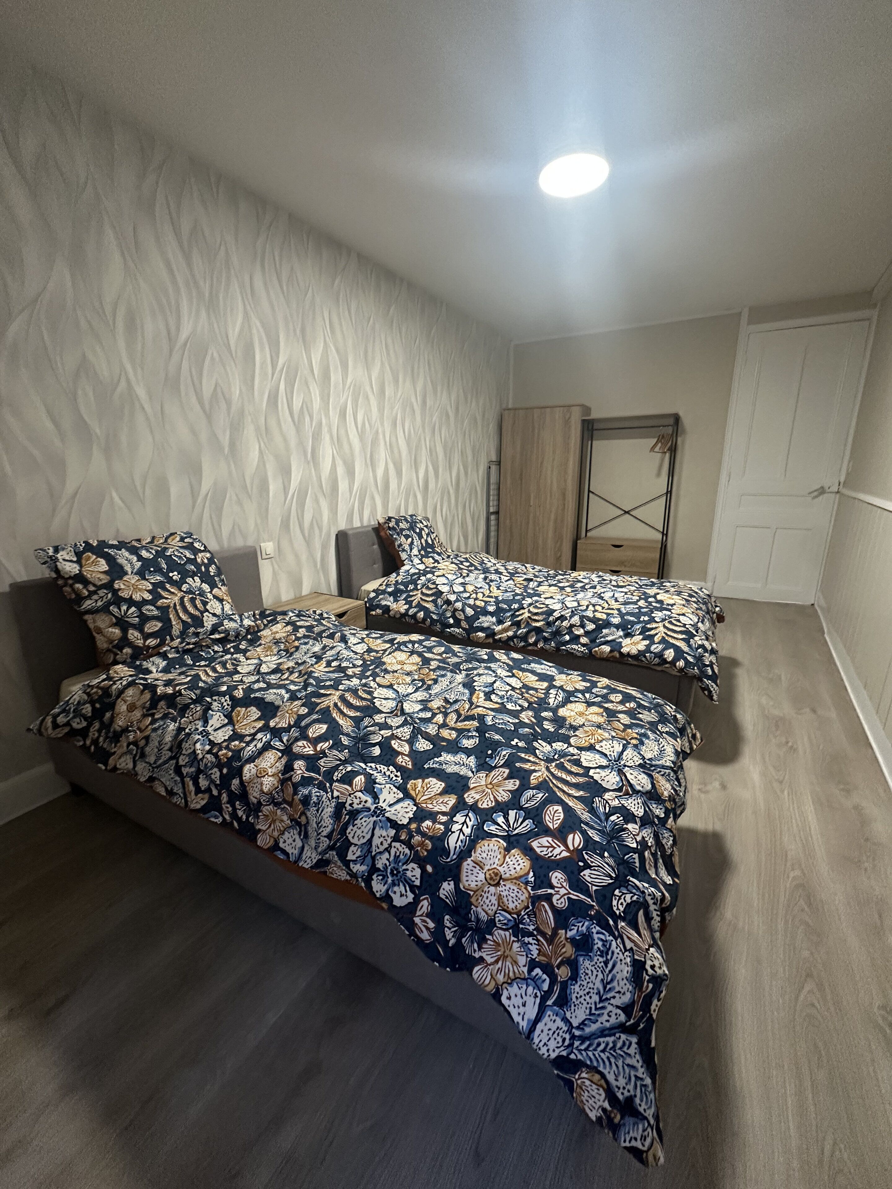 Een slaapkamer met twee bedden, een kledingkast en een deur.