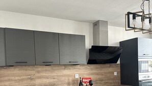 Eine moderne Küche mit grauen Schränken, einer Holz Arbeitsplatte, einer schwarzen Spüle, einer Weinflasche und einem Weinglas.
