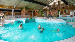 En inomhuspool med flera banor, ett avgränsat lekområde med nät och en väggmålning med tropiskt tema.