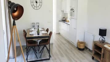 A modern kitchen with white cabinets, a dining table set for four, and a clock on the wall.