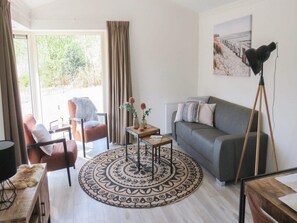 Un salon comprenant un canapé, un fauteuil, une table basse et un lampadaire.