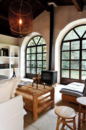 A cozy room with a fireplace, wooden furniture, and large arched windows. - 17th-century house below Saint-Montan castle (Saint-Montan)
