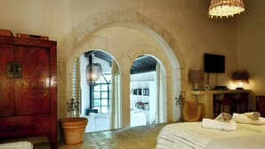 A bedroom with a large bed, a wooden wardrobe, a potted plant, and a television on the wall. - 17th-century house below Saint-Montan castle (Saint-Montan)
