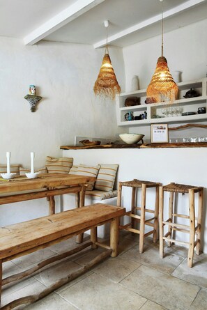 Un intérieur rustique avec des meubles en bois, un mur blanc et des luminaires suspendus.