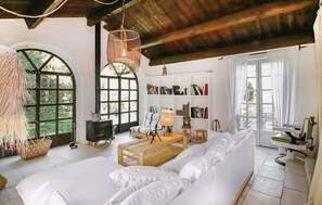 Un salon spacieux avec un grand canapé blanc, une table basse en bois et une bibliothèque remplie de livres.