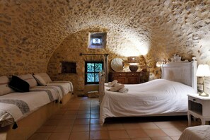 A bedroom with a stone ceiling, a bed, a bedside table, and a window. - 17th-century house below Saint-Montan castle (Saint-Montan)