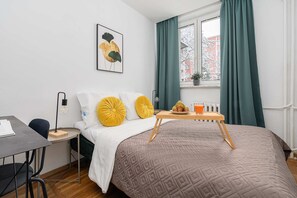 A bedroom with a bed, a bedside table with a lamp, a window with curtains, and a wall-mounted picture. - Family Stay on Boguckiego (Warsaw)