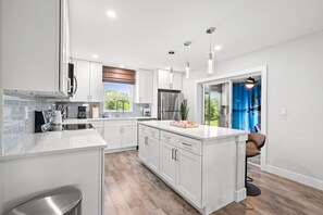 A modern kitchen with white cabinetry, stainless steel appliances, and a large island. - Wellness Retreat 2 Min to Warm Mineral Springs (North Port)