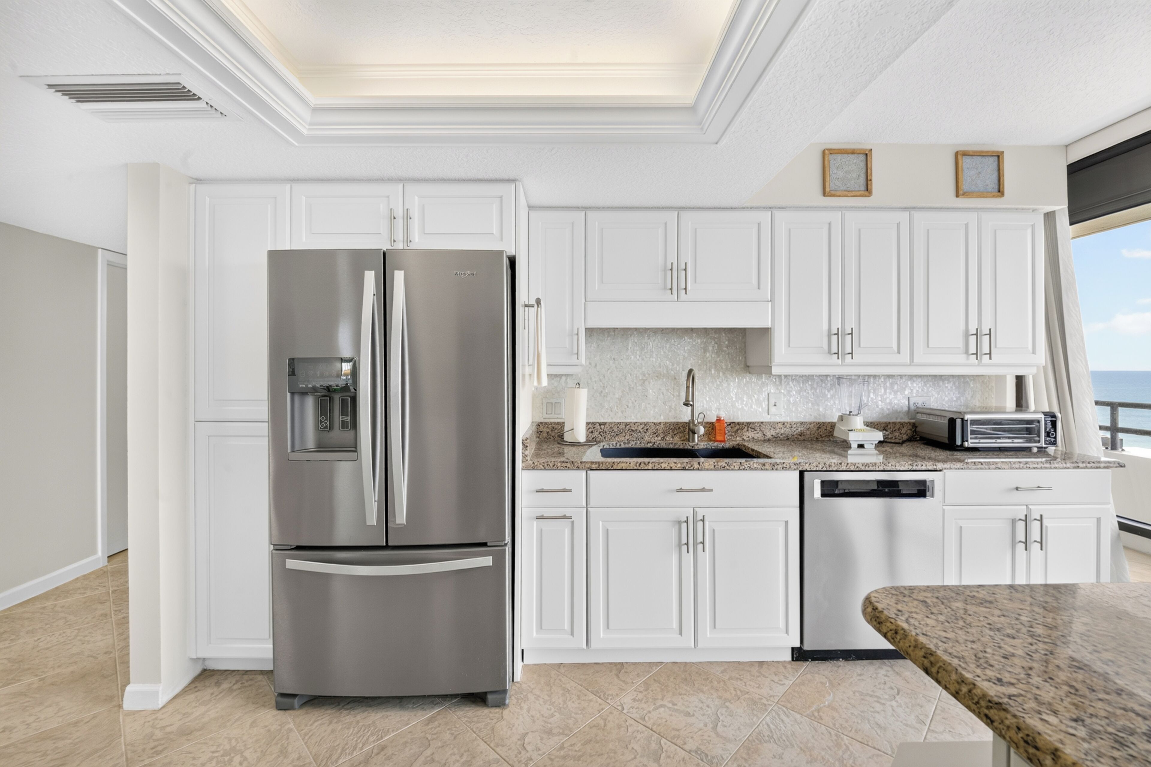 Una cocina moderna con armarios blancos, electrodomésticos de acero inoxidable y encimera de granito.