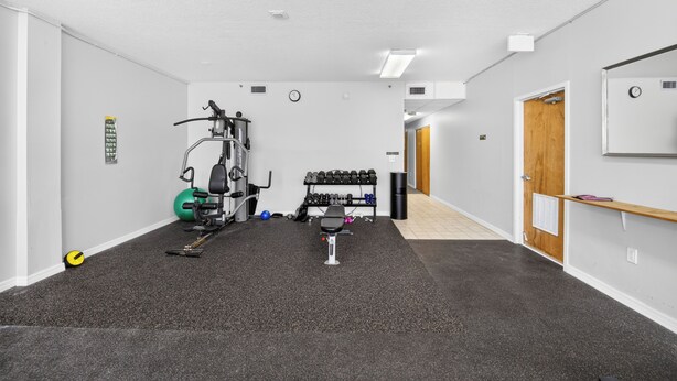 Ett gym med träningsutrustning, en väggklocka och en dörr.