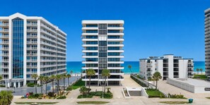 A multi-story hotel with a central atrium, a beach view, and a parking area. - Ocean/River View | Heated Pool | Royal Atlantic 8D (Daytona Beach)
