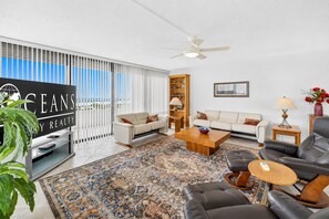 A modern living room with a sofa, coffee table, and a television. - Ocean/River View | Heated Pool | Royal Atlantic 8D (Daytona Beach)