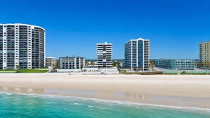 A beachfront hotel with multiple high-rise buildings, a sandy beach, and clear blue waters. - Ocean/River View | Heated Pool | Royal Atlantic 8D (Daytona Beach)