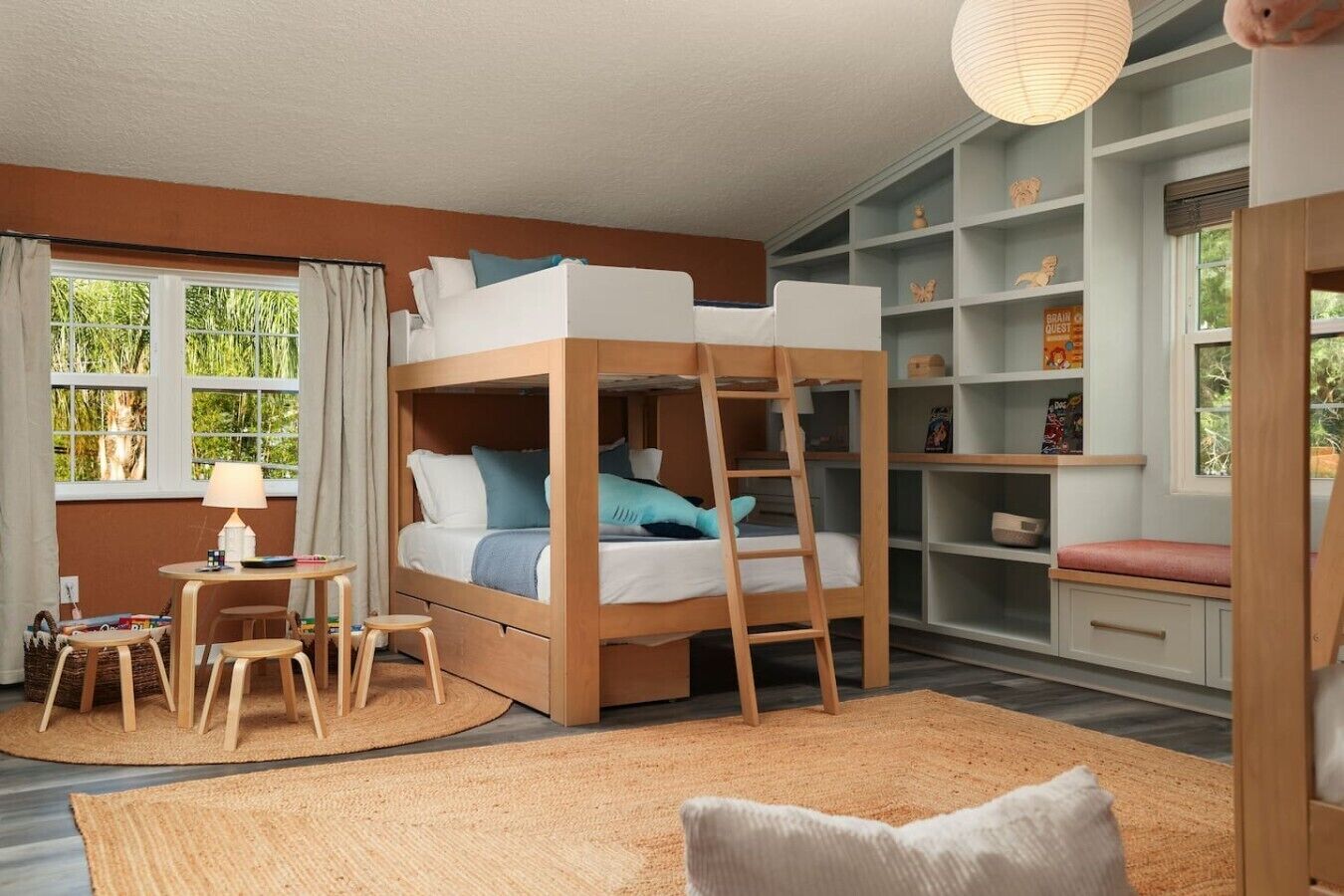 A bunk bed with a ladder, a desk with a chair, and a bookshelf.