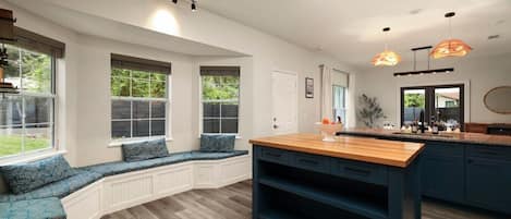 A kitchen with a built-in bench seating area, wooden countertops, and pendant lighting.