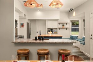 A modern kitchen with a central island, bar stools, and pendant lighting. - Fire Pit & Patio • 10 Min to Historic Downtown (St. Augustine)