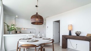 A modern dining area with a round table, chairs, a hanging light fixture, and a fireplace with a lamp. - Infinity Blue – Rooftop Pool & Sea Views | Fuengirola (Fuengirola)