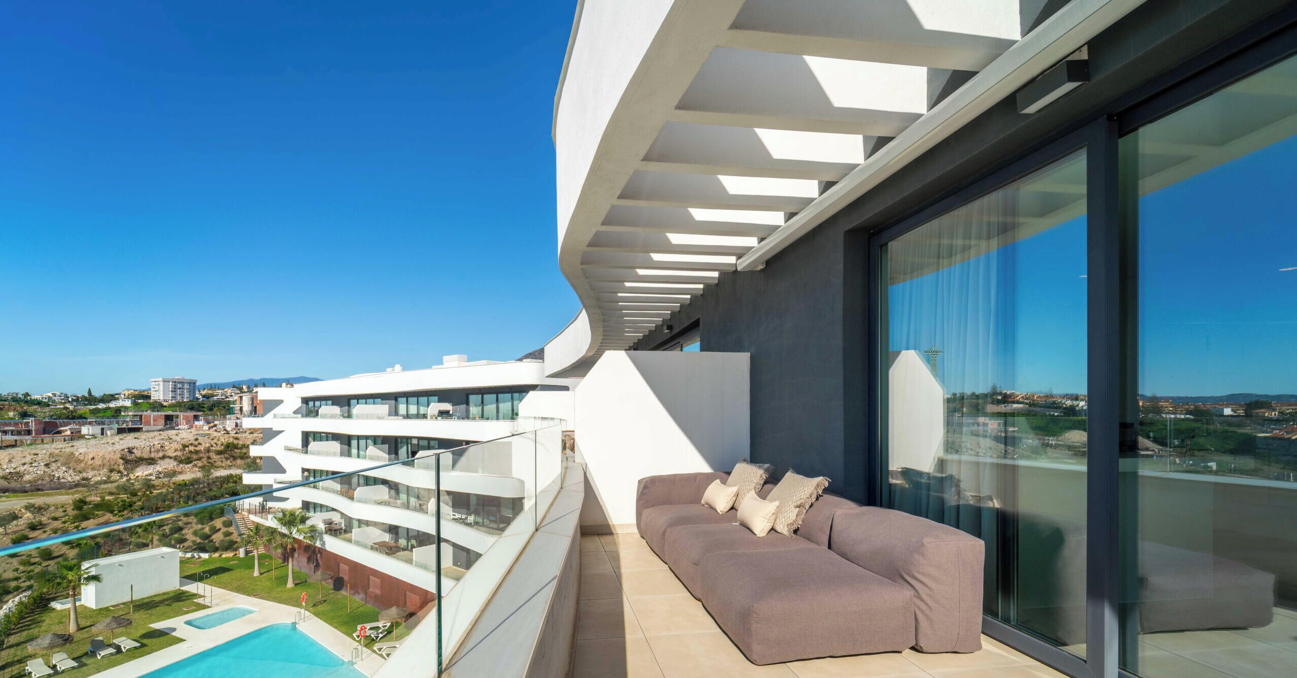 A modern balcony with a sofa and a pool.