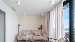 A modern living room with a sofa, a lamp, and a view of the outdoors. - Infinity Blue – Rooftop Pool & Sea Views | Fuengirola (Fuengirola)