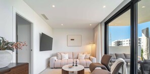 A modern living room with a sofa, a coffee table, and a TV mounted on the wall. - The Garden Escape 2bedroom garden unit (Fuengirola)