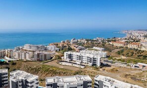 Paisatge urbà costaner amb edificis residencials, cel blau clar i el mar al fons.