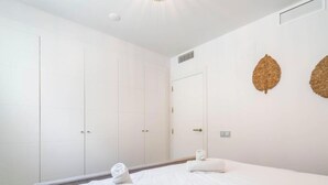 A hotel room with a bed, a wardrobe, and two wall-mounted decorative items. - Casa Lara — Andalusian Village Retreat (Benalmádena)