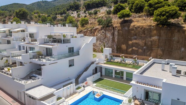 A modern residential building with multiple balconies, a swimming pool, and a view of a cliff and forested hills. - Casa Lara — Andalusian Village Retreat (Benalmádena)