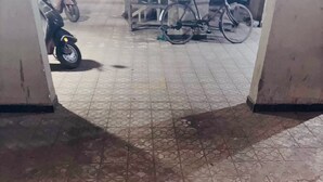 Piso de azulejos com um padrão geométrico e uma porta entreaberta que dá para outro cômodo.