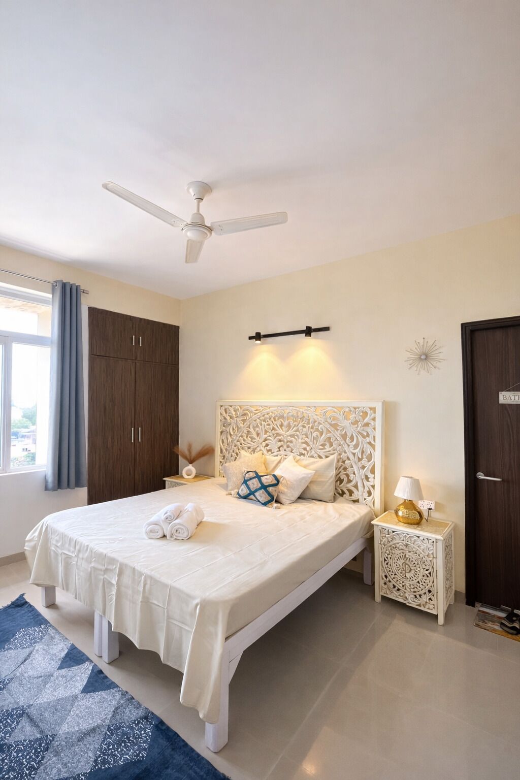 Une chambre à coucher comprenant un lit, un ventilateur de plafond, une table de chevet, une lampe et une armoire.