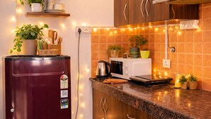 Uma cozinha com armários de madeira, geladeira, micro-ondas e luzes de fada.