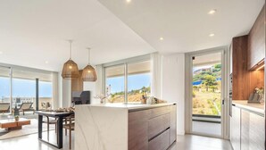 A modern kitchen with a large island, pendant lighting, and a view of the outdoors. - Casa Aura Higuerón  -Modern Luxury Apartment with Spectacular valley and sea views- Higueron - Fuengirola (Fuengirola)