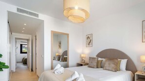 A hotel room with a bed, bedside tables, a mirror, and a hanging light fixture. - Casa Lisa-New 3bed with stunning Sea-views in Fuengirola (Fuengirola)