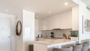A modern kitchen with white cabinetry, a central island, and a dining area with grey upholstered chairs. - Casa Lisa-New 3bed with stunning Sea-views in Fuengirola (Fuengirola)