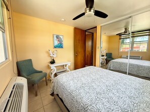 A hotel room with two beds, a desk, a chair, a ceiling fan, and a window. - 3-bedroom condo in beach town of Rincón with pool and AC at Sea Beach Village (Rincón)