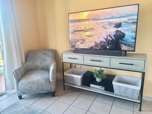 A living room with a sofa, a TV on a stand, and a small plant. - 3-bedroom condo in beach town of Rincón with pool and AC at Sea Beach Village (Rincón)