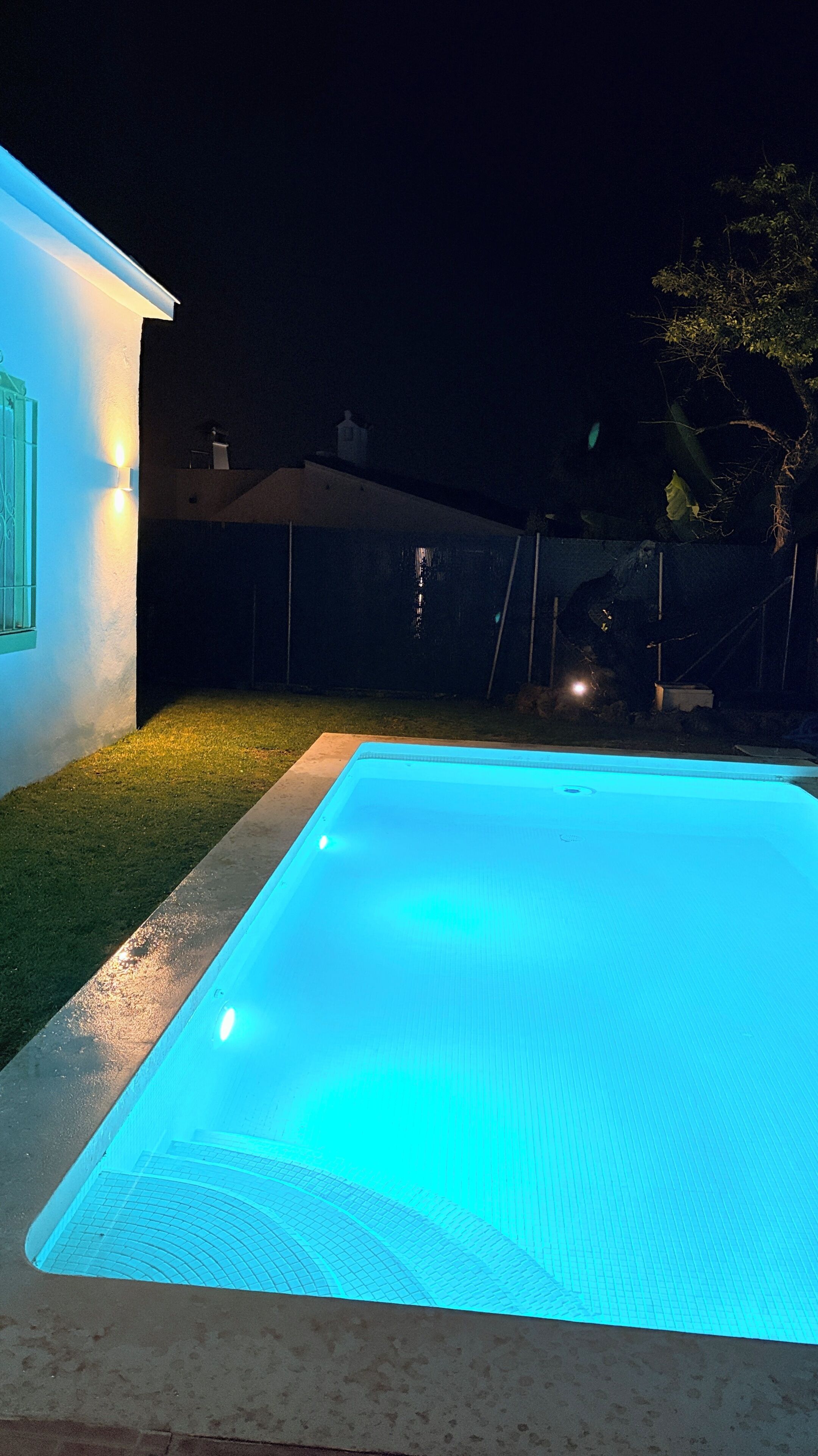 Une piscine illuminée de lumière bleue, la nuit.