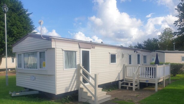 A mobile home with a porch and a small deck, featuring a ramp for accessibility. - 10 Berth Caravan Butlins Skegness Pet Friendly (Skegness)