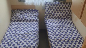 Two twin beds with star-patterned bedding in a room with a window and curtains. - 10 Berth Caravan Butlins Skegness Pet Friendly (Skegness)
