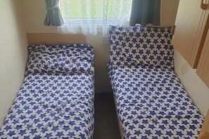 Two twin beds with star-patterned bedding in a room with a window and curtains.