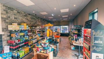 A grocery store interior with shelves stocked with beverages, snacks, and a refrigerated section.