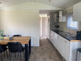 Una cocina compacta con comedor, que incluye una mesa de madera, sillas negras y un horno empotrado.