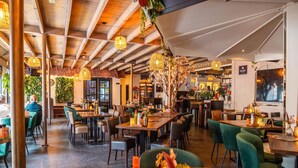 Un restaurante con vigas de madera, mesas con velas y plantas.
