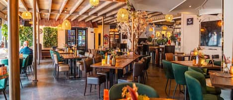 Un comedor interior con mesas, sillas e iluminación colgante.