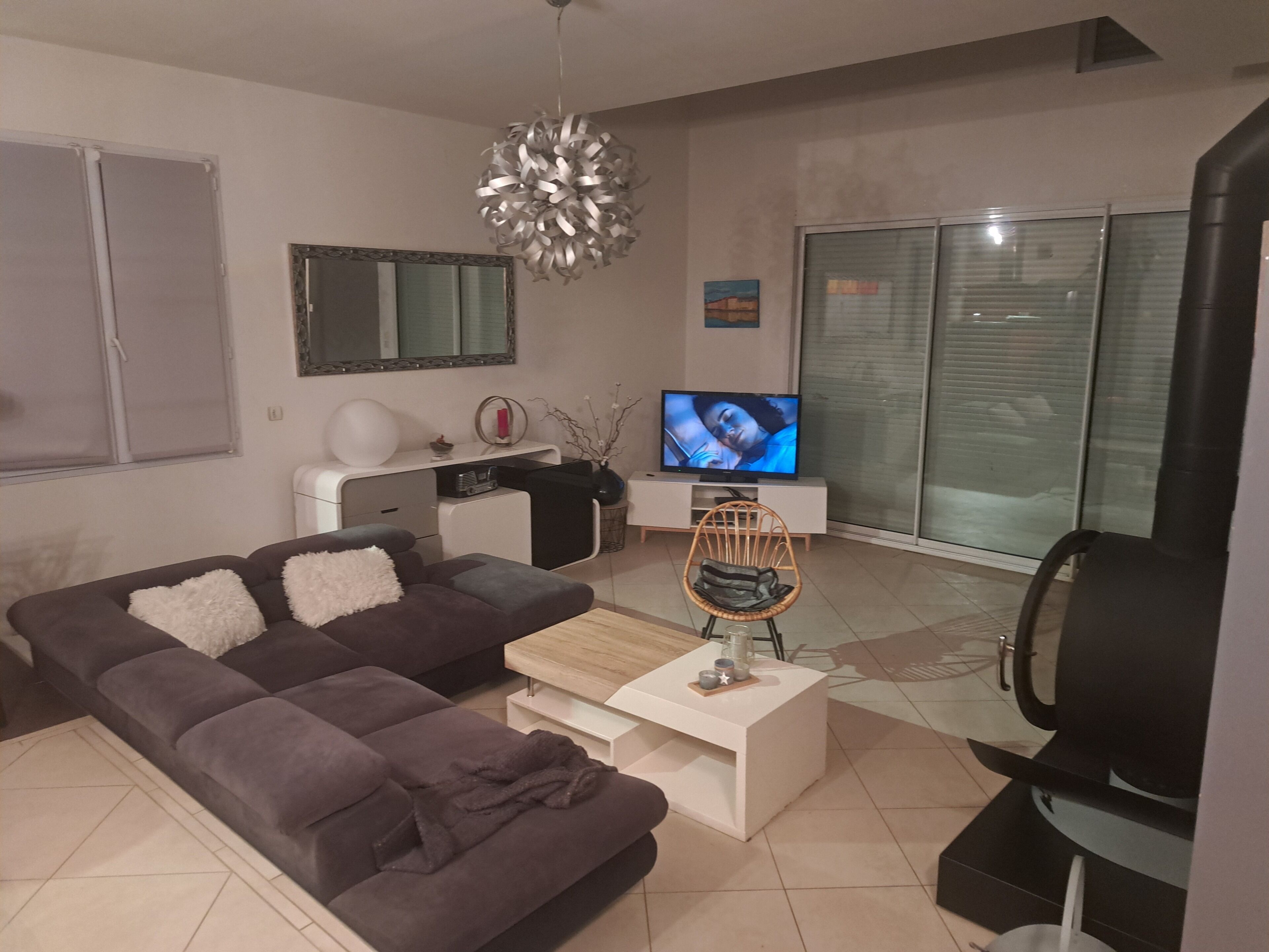 A modern living room with a sofa, a coffee table, a TV, and a fireplace.