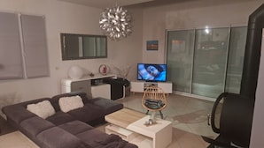 A modern living room with a sofa, a coffee table, a TV, and a fireplace. - 140 m2 fenced house (Pouzac)