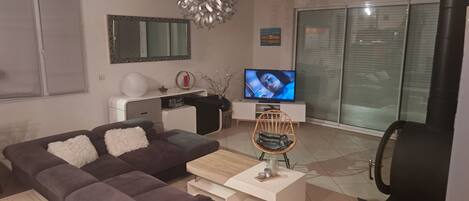 A modern living room with a sofa, a coffee table, a TV, and a fireplace.