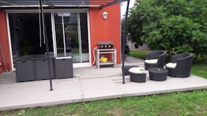 An outdoor patio area with a grill, seating, and a glass door entrance. - 140 m2 fenced house (Pouzac)