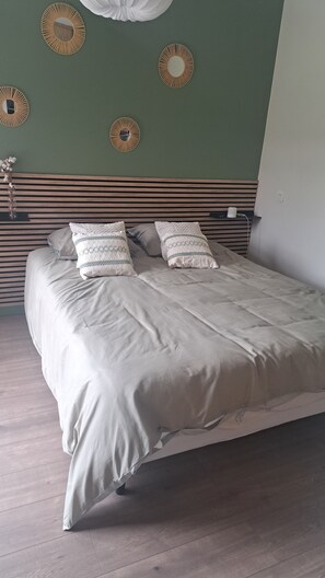 Ein ordentlich bezogenes Bett mit einem hölzernen Kopfteil, einer Blumenvase und wandmontierten Spiegeln.