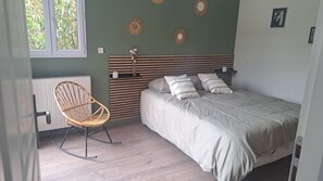 A bedroom with a bed, a rocking chair, a radiator, and wall decorations. - 140 m2 fenced house (Pouzac)