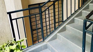 A staircase with black railings leading to an upper floor. - Veena Homes | Studio Airbnb in Nairobi (Nairobi)